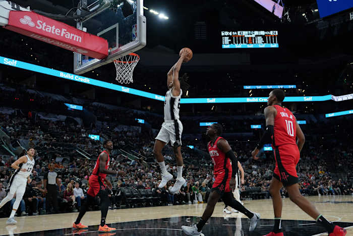 Oct 18, 2023; San Antonio, Texas, USA; San Antonio Spurs guard Devin Vassell (24) goes up for a dunk in front of Houston Rockets guard Aaron Holiday (0) in the first half at the Frost Bank Center.